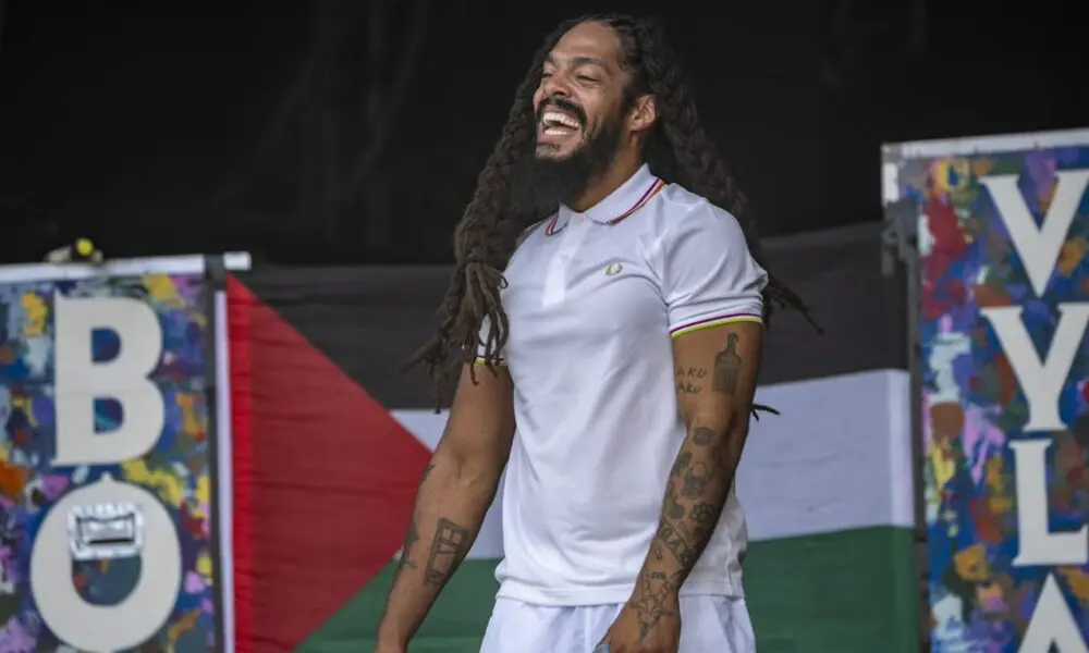 Με φόντο μια παλαιστινιακή σημαία, ο Bobby Vylan εμφανίζεται στη σκηνή West Holts την τέταρτη ημέρα του φεστιβάλ Glastonbury στις 28 Ιουνίου 2025.