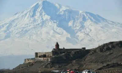a castle on a hill with a snow covered mountain in the background
