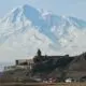 a castle on a hill with a snow covered mountain in the background