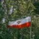 Iranian flag waving amidst green trees