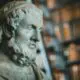 Close-up of a classical marble statue with blurred bookcases in the background.