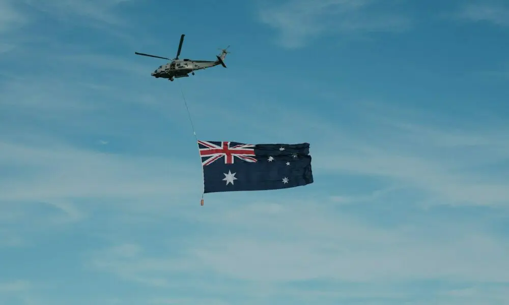 A helicopter flying next to a flag flying in the sky
