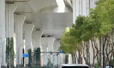 Cars driving under elevated highway in Shanghai, China during daytime.