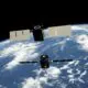 Two satellites with solar panels orbiting above the blue Earth with white clouds