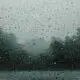 Raindrops on a window pane with blurred trees in the background